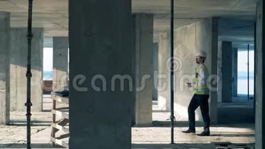 穿工作服的工程师正沿着<strong>正在施工</strong>中的建筑物行走。